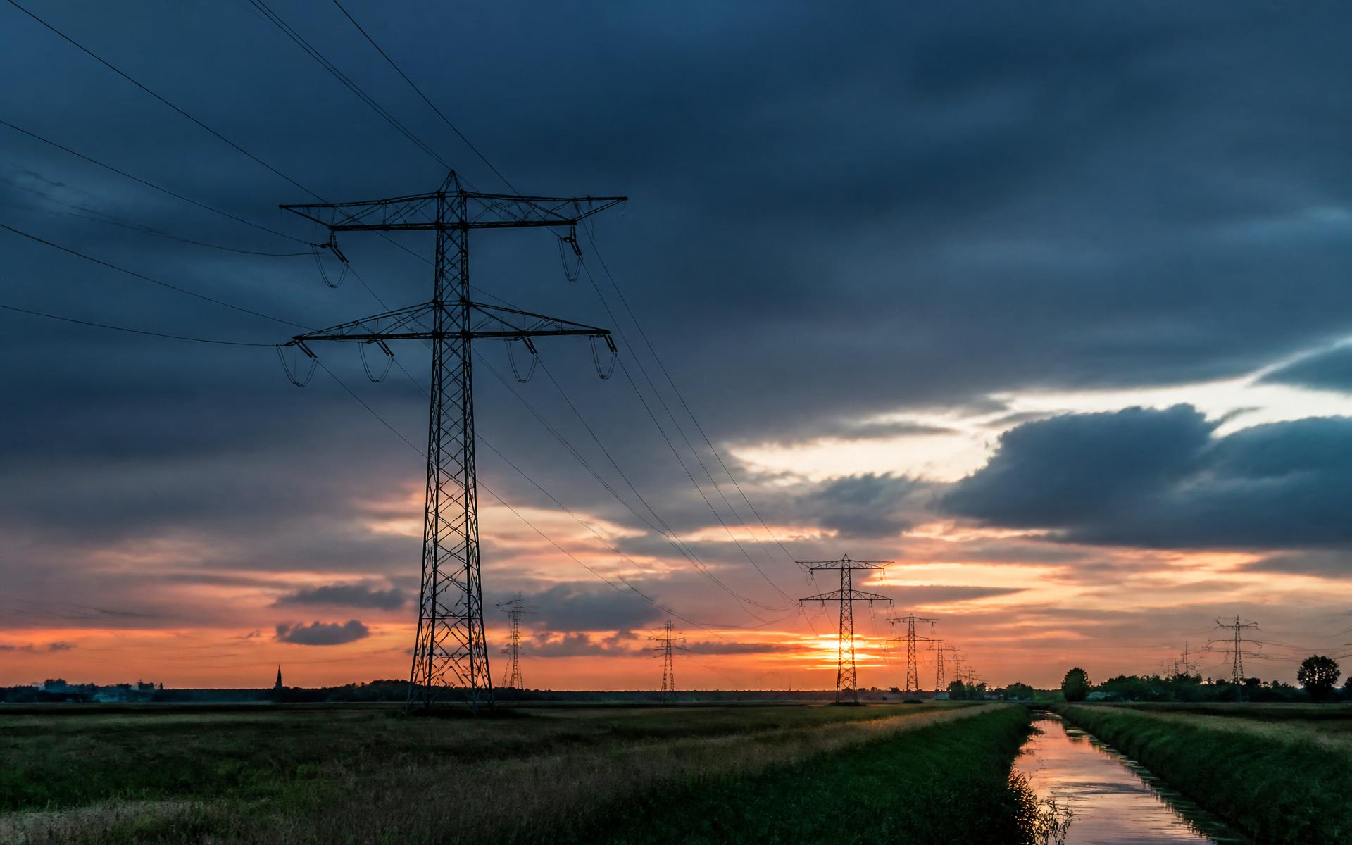 Hoogspanningslijnen in een Nederlands polderlandschap bij zonsondergang